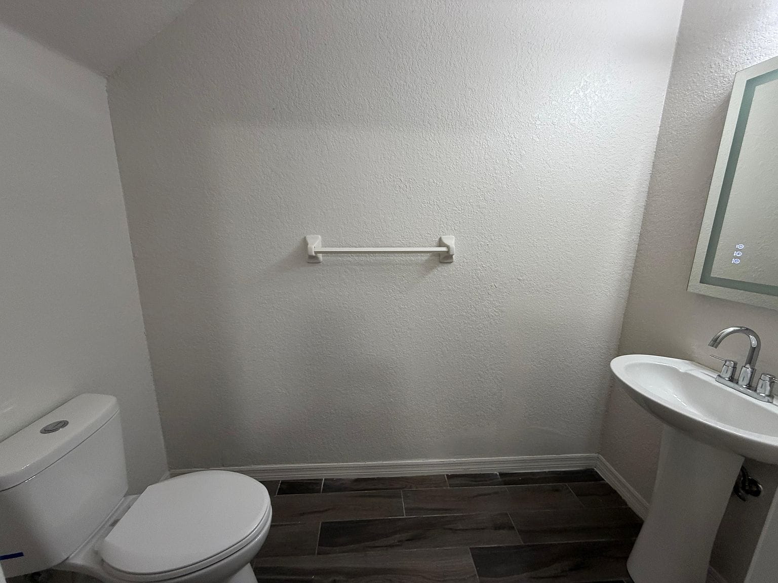 Medio baño con lavabo de pedestal e inodoro