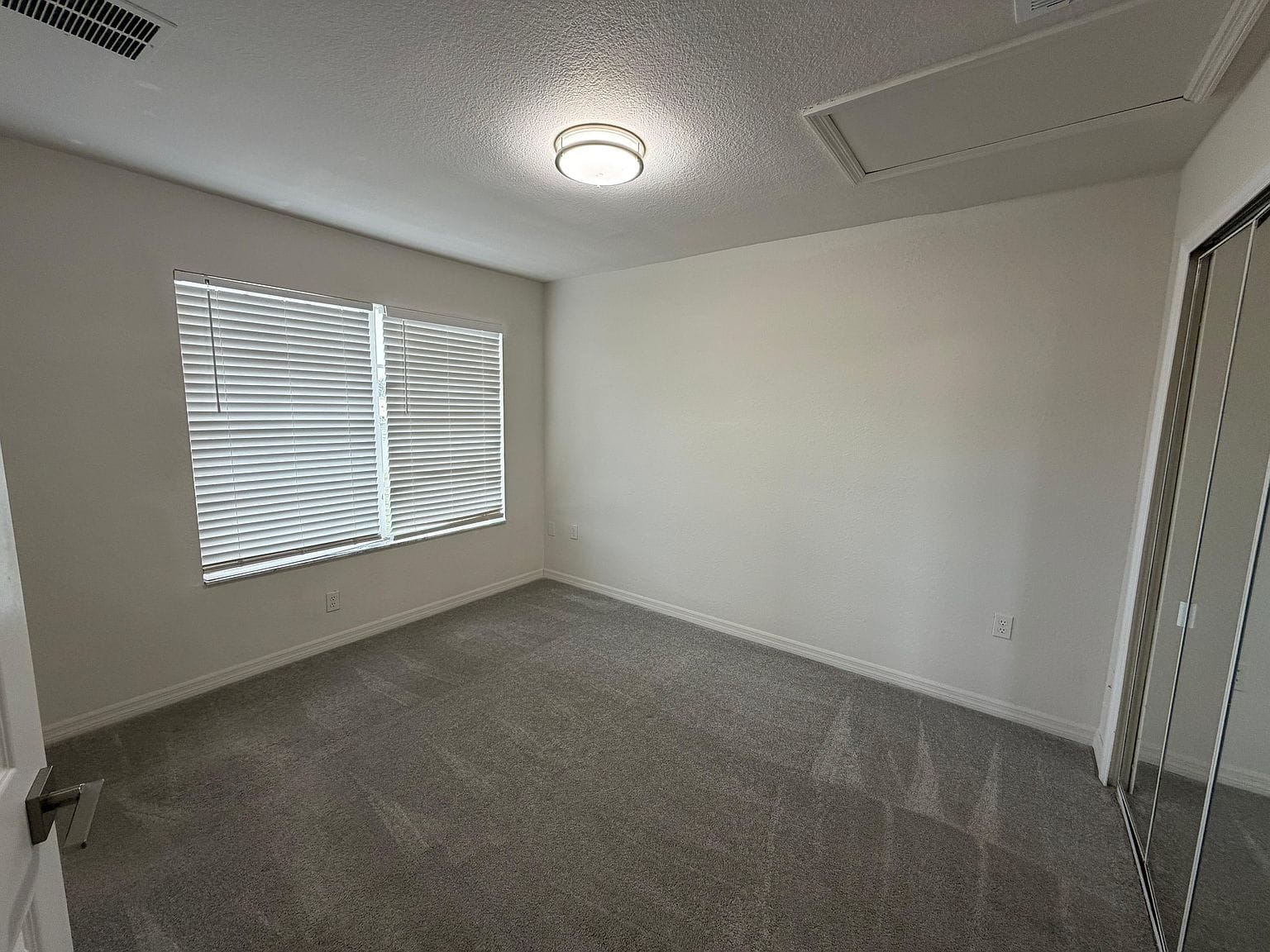 Habitación alfombrada con ventana y clóset