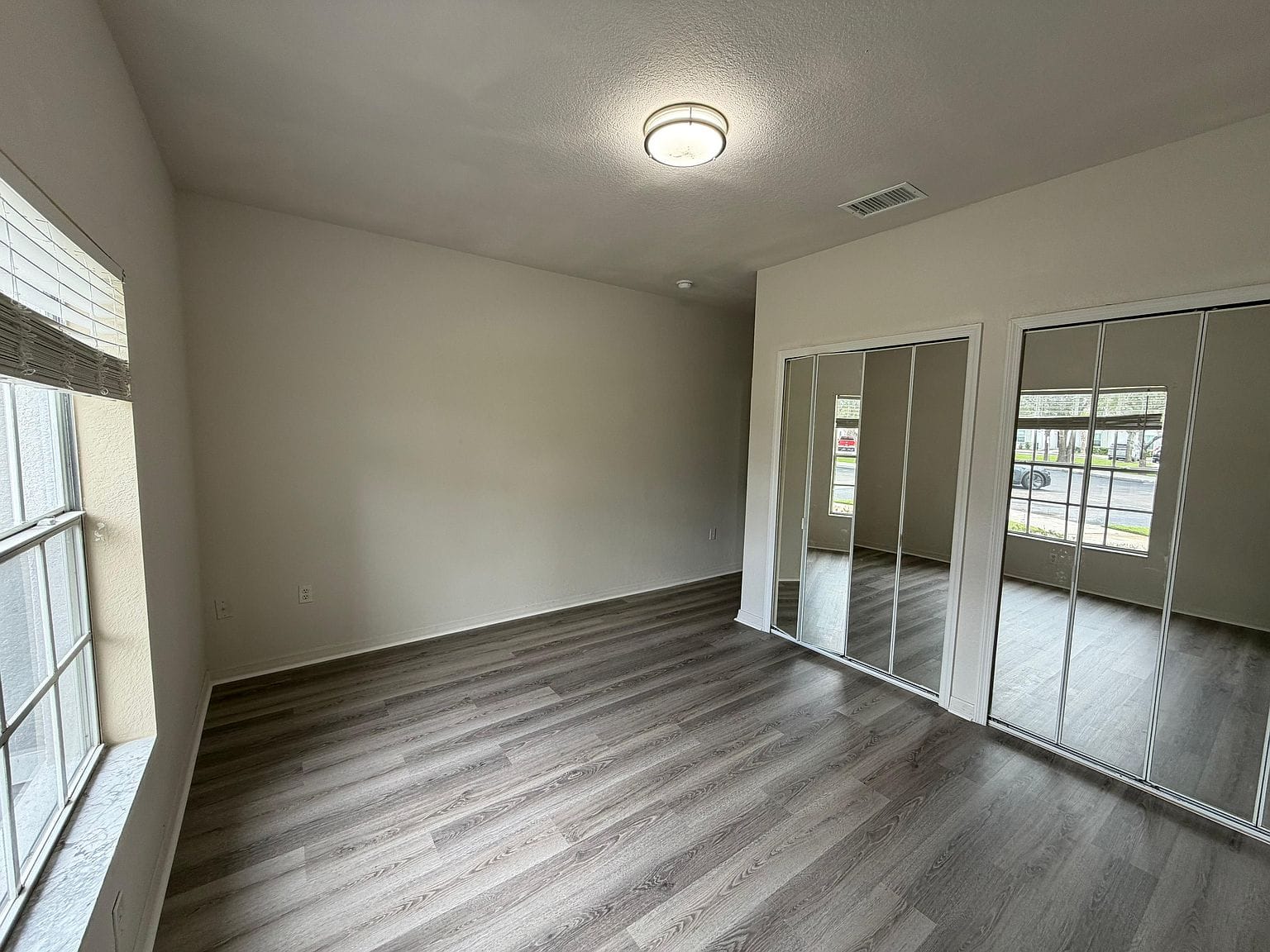 Habitación con clóset de puertas de espejo y puerta corrediza de vidrio